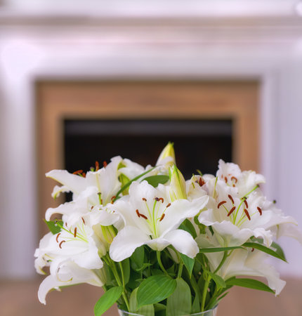 Closeup of a bouquet of lily flowers in a vase on a table at home. Bunch of white Lilium flowering plants blooming in a jar in the living room. Lilies on display in a vessel in the lounge in a houseの写真素材