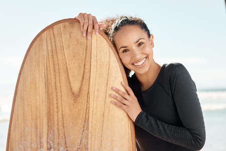 When the surfs up, your life is too. Shot an attractive young woman posing with her surfboard and going out to surf at the beach.の写真素材