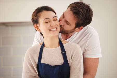 You should know just how special you are to me. Shot of a man kissing his wife on her cheek at home.の写真素材