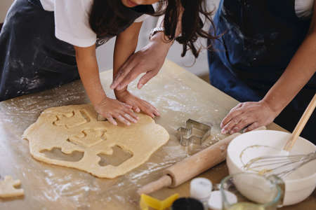 Kids love to bake. Shot of a little girl pressing out cookies with a cookie cutting.の写真素材