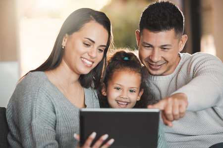 Family is what you make it. Shot of a young family happily bonding while using a digital tablet...