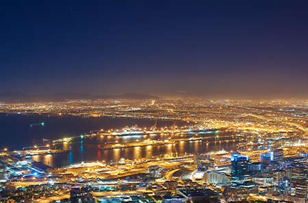 Copyspace with dark night sky over a cityscape and ocean view in Cape Town, South Africa. Scenic panoramic landscape of lights illuminating a metropolitan skyline in the city centre at nightの写真素材