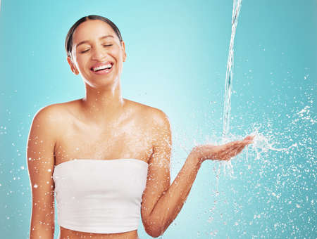 Wake up, wash up. Shot of an attractive young woman showering against a blue background.の写真素材
