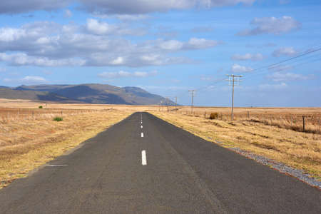 Landscape of tar road leading past freshly harvested farm in Western Cape, South Africa. Blue sky, scenic rural countryside street of ploughed agricultural field. Travel to sustainable grain pastureの写真素材
