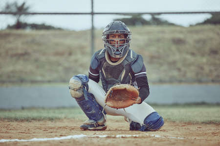 Portrait african american pitcher ready to make a catch with a mitt on a baseball field. Young sportsman in a helmet ready for the ball. Black man athlete playing a game or match on pitch outdoorsの写真素材