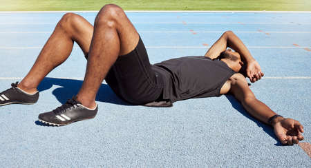 Closeup of a fit active young male athlete lying exhausted flat on the track after a race and...
