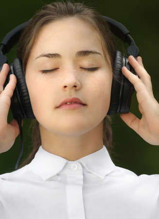 The allure of the rhythm. Shot of a young woman listening to music in the park.