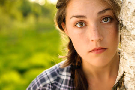 At peace with nature. Shot of a beautiful young woman leaning against a tree in a forest.の写真素材