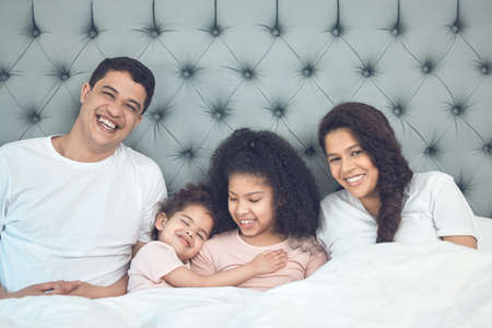 Blissful mornings. Shot of a beautiful young family talking and bonding in bed together.の写真素材