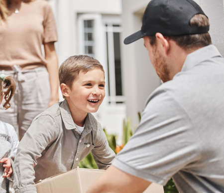 Im the man of the house. Cropped shot of an adorable little boy collecting his mothers delivery from a male courier.の写真素材