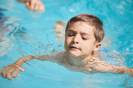 Finding his way. High angle shot of an adorable little boy swimming outside.