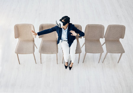 Immersed in a whole new world. High angle shot of a young businesswoman wearing a VR headset while sitting in line in an office.の写真素材