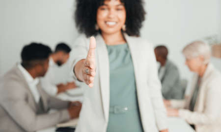 Giving you a warm welcome. Shot of a young businesswoman extending her hand out for a handshake at work.の写真素材