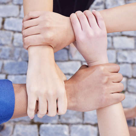 Team spirit is knowing and living the belief. Cropped shot of a group of businesspeople linking their arms in solidarity at work.の写真素材