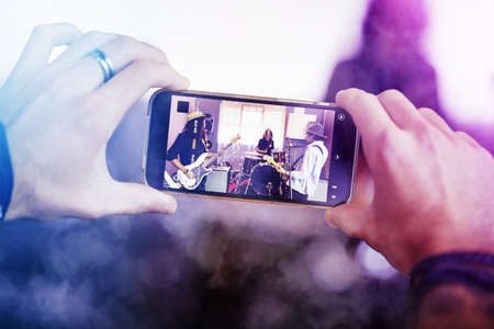 Capturing the concert. Cropped shot of an unrecognizable male fan recording a concert on his cellphone.の写真素材