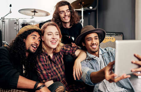 Selfies with the band. Cropped shot of a band taking selfies with a tablet before their gig.の写真素材