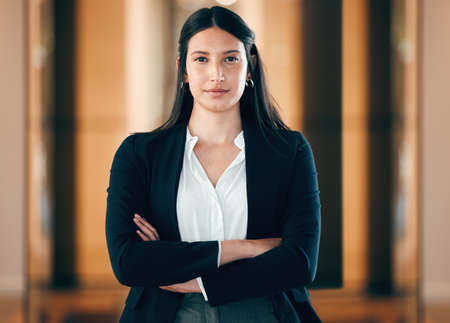 I take this seriously. Shot of a young businesswoman standing with her arms crossed at work.の写真素材