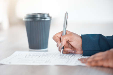 Filling out a business application. Cropped shot of an unrecognizable businesswoman filling out forms while working at her desk in the office.の写真素材