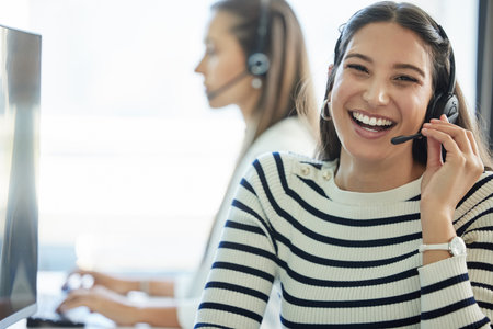 Shes having a good day. Shot of a young woman wearing a headset while working in a call center.