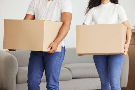 Ill help lighten the load for you. Shot of a young couple holding boxes in their new house.の写真素材
