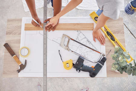 Weve divided our entire renovation into sub-plans. Shot of two people discussing a blueprint.