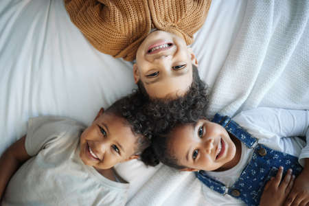 Someday, the world will know their names. Portrait of three siblings bonding in bed at home.の写真素材