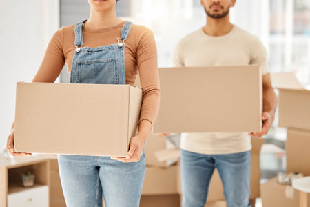 Lets pack up and go. Closeup shot of an unrecognisable couple carrying boxes while moving house.
