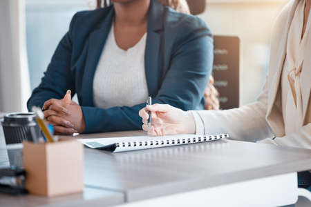 In the hot seat. Cropped shot of two unrecognizable businesswomen sitting at the boardroom table...