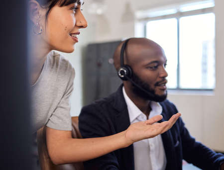 Lets try and troubleshoot this together. Shot of two call centre agents working together in an...