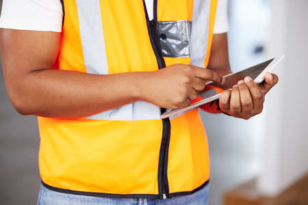 A quick check on our progress. Cropped shot of an unrecognizable contractor using a digital tablet at work.の写真素材