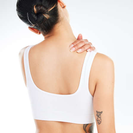 .. Studio shot of an unrecognizable woman experiencing back pain after working out against a white...