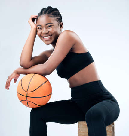 Ive been balling all day. Studio shot of a sporty young woman posing with a basketball against a studio background.の写真素材