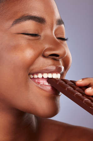 Ive been craving this. Studio shot of a beautiful young woman biting a piece of chocolate.の写真素材