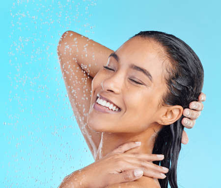 The results will astonish you. Shot of an attractive young woman showering against a blue background.の写真素材