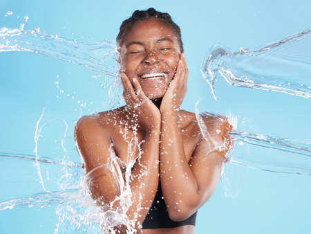 Her warmth will draw you in. Shot of a beautiful young woman being splashed with water against a...