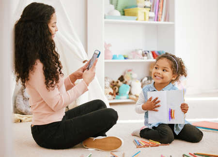 My daughter is the most important thing in my life. Shot of mother taking a photo of a her daughter at home.の写真素材
