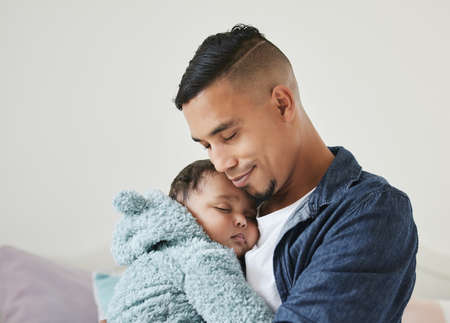 Ill protect you forever. Shot of a young father embracing his baby at home.の写真素材