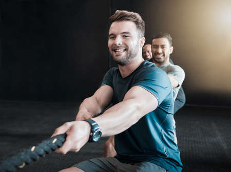 Its all in the name of fun. Shot of a group of gym partners pulling a rope in tug of war together.の写真素材
