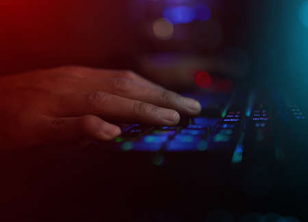 Its all about timing. Cropped shot of an unrecognizable male gamer playing video games in a dark...