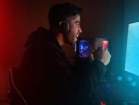 Onto the next round. Cropped shot of a handsome young male gamer playing video games in a dark room.