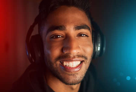 This is my gameface. Cropped shot of a handsome young male gamer playing video games in a dark room.の写真素材