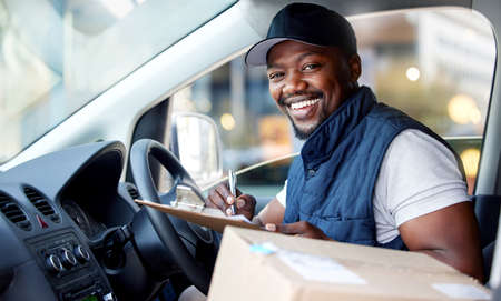 Your parcel is on its way. Shot of young man delivering a package while sitting in a vehicle.の写真素材