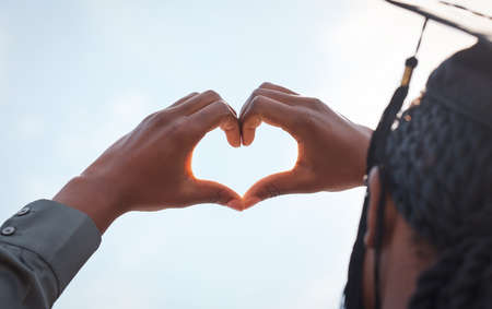 I am going to soar higher and higher. Closeup shot of a young woman making a heart shape with her hands on graduation day.の写真素材