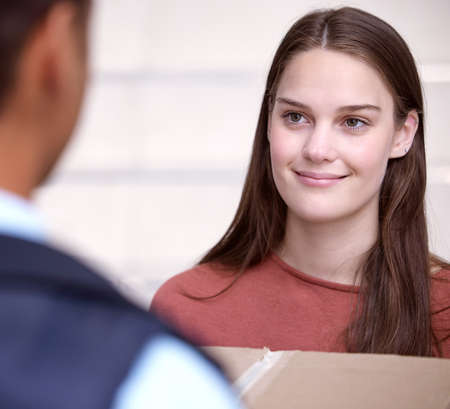Your wish is my command. Shot of a woman accepting her delivery from the delivery man.の写真素材