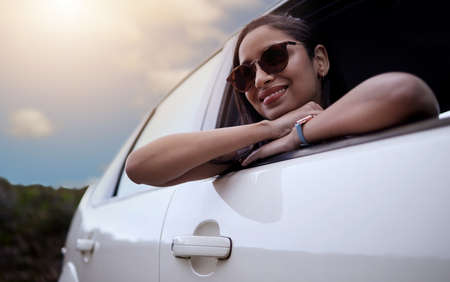 The road is where my heart is. Shot of a beautiful young woman enjoying an adventurous ride in a car.の写真素材