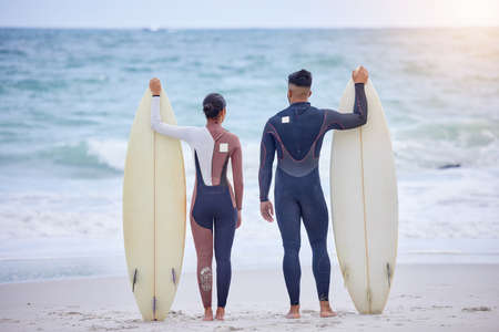 Brave and free and wild as the sea. Rearview shot of a young couple surfing together at the beach.の写真素材