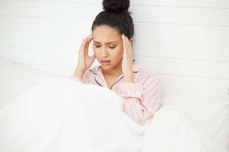 I cant take it anymore. Shot of a young woman looking stressed while sitting in bed.の写真素材