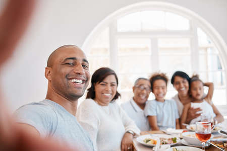 Youll always have these memories. Shot of a young man taking a selfie with his family during lunch.