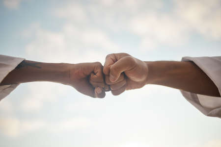 Power up. Closeup shot of two unrecognisable people giving each other a fist bump outdoors.