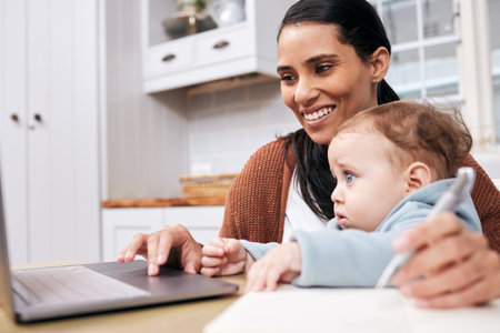 Moms run the world. Shot of a young woman going through paperwork while holding her son at home.の写真素材